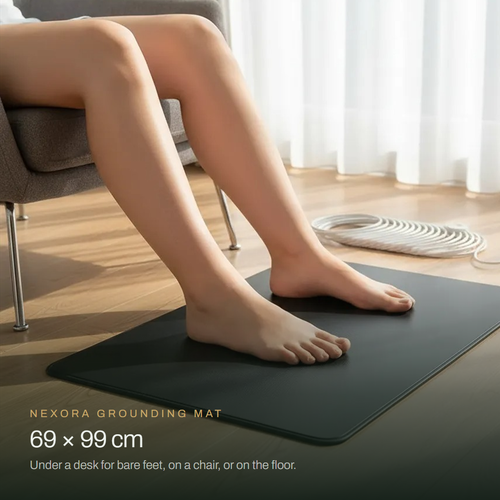 Bare feet resting on the Nexora grounding mat, 69 x 99 cm, beside an armchair